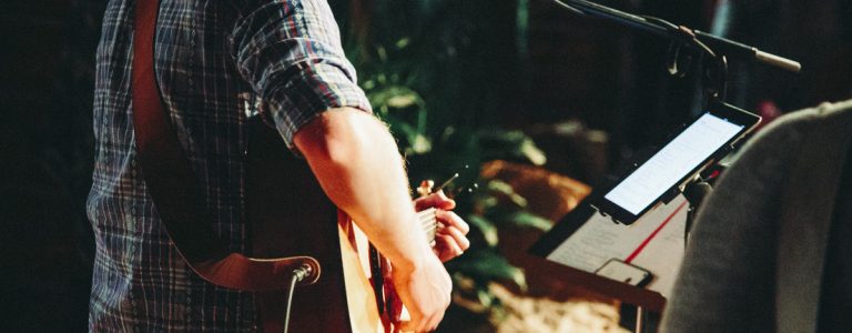 Man playing guitar and reading music from ipad